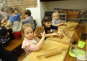 Dzieci układają ciasto na formach.